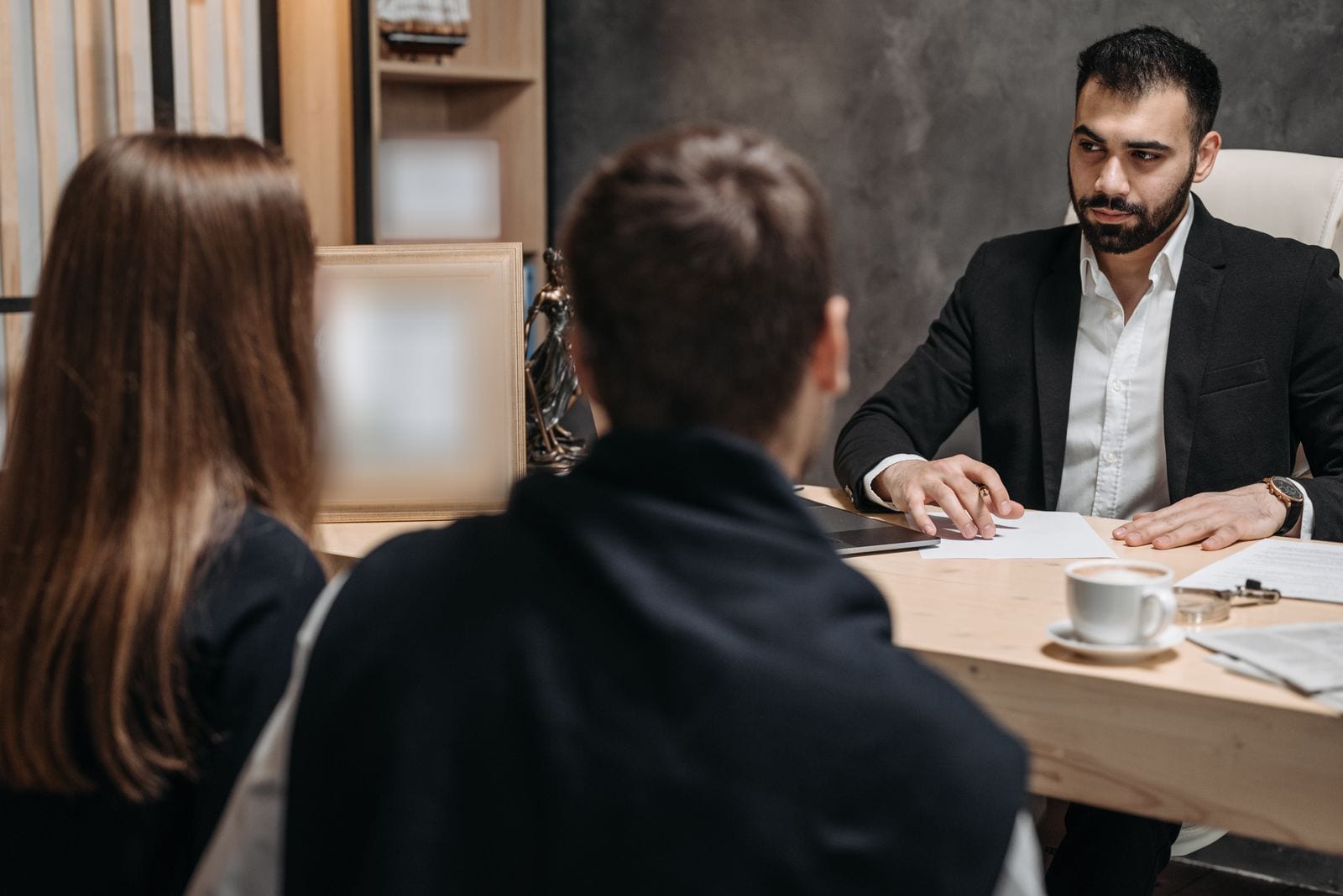 Two clients meeting a legal professional at an office desk