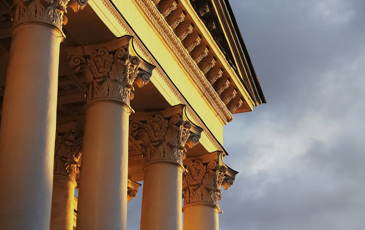 A building with columns and a clock on the side of it
