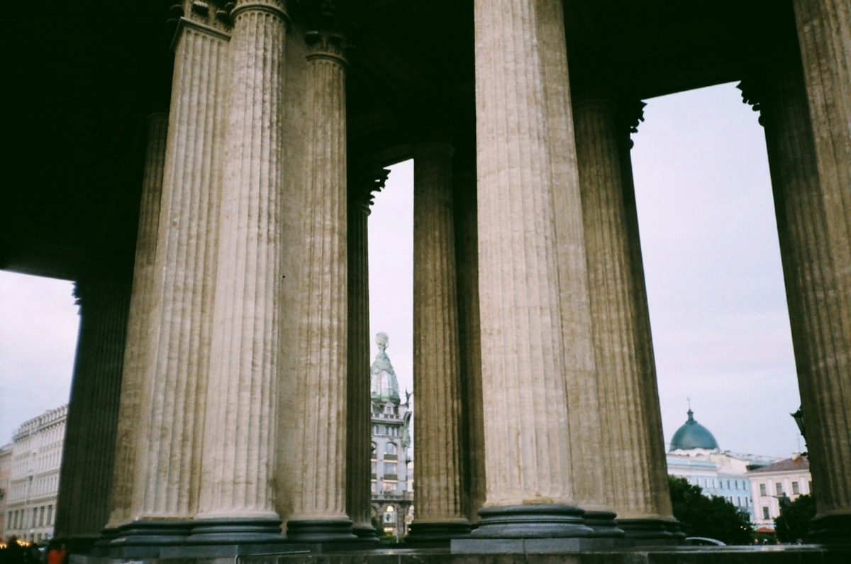 a group of pillars with a clock tower in the background