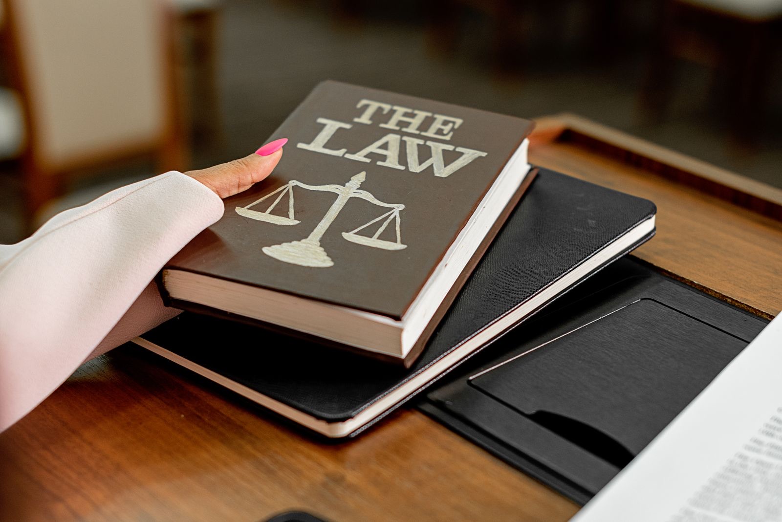 A law book beside the scales of justice on a wooden desk
