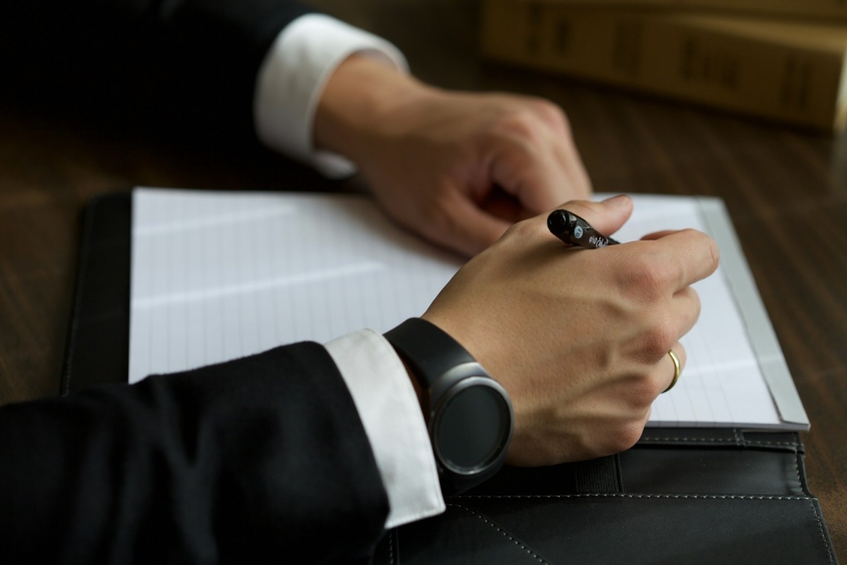 A person in a suit writing on a document