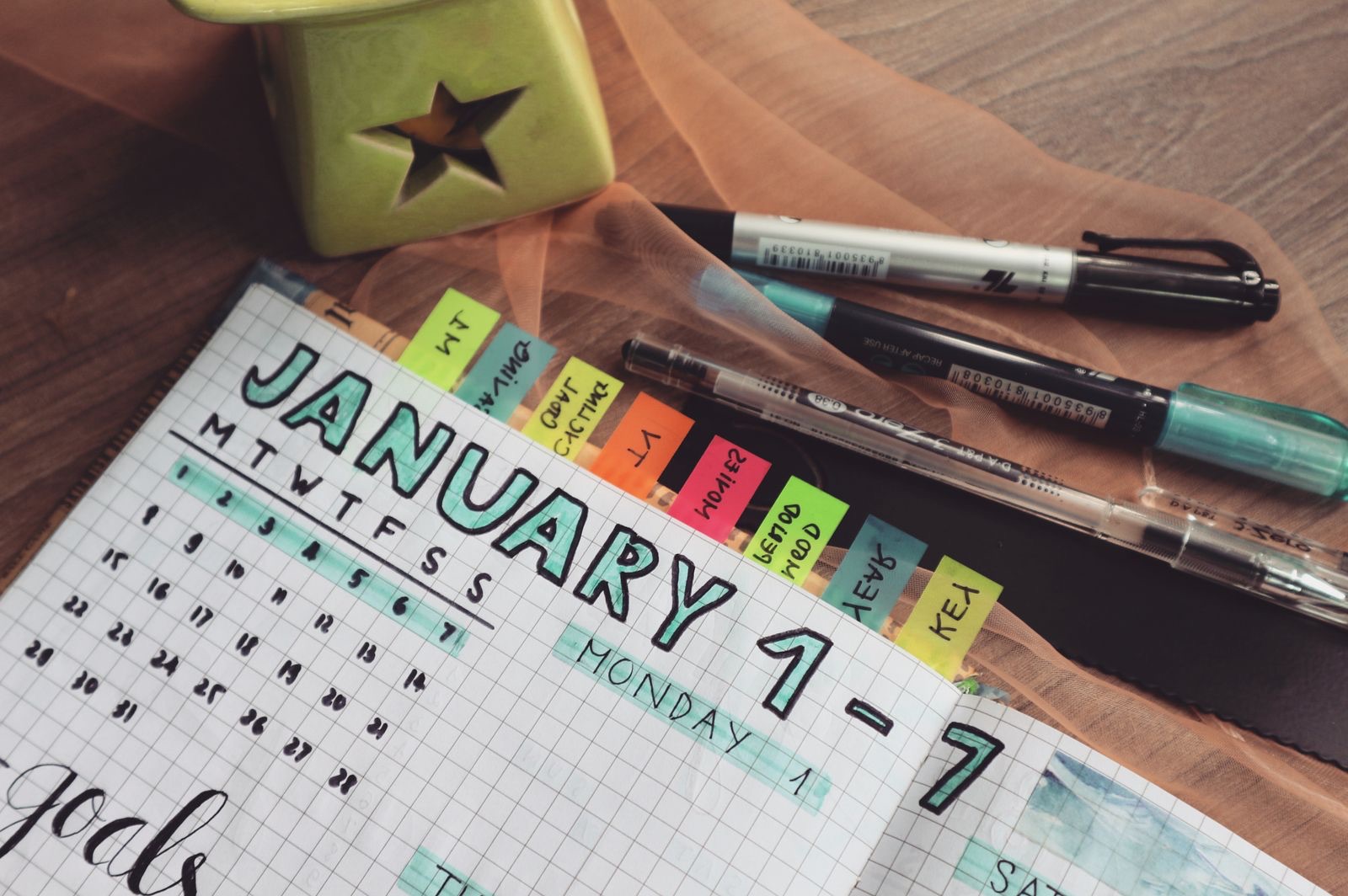 A planner with coloured tabs and pens