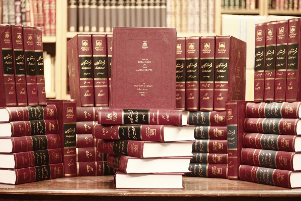 A stack of red books sitting on top of a wooden table