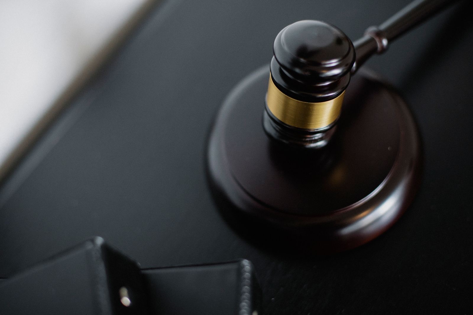 A wooden gavel on a courtroom table beside case folders