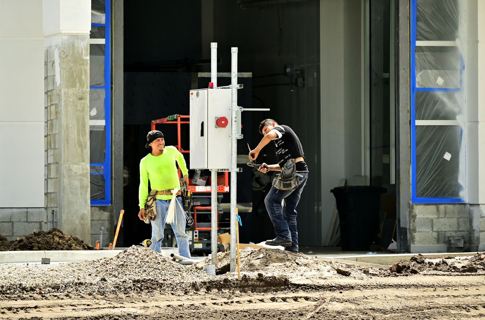 Construction workers in safety gear installing an electrical panel