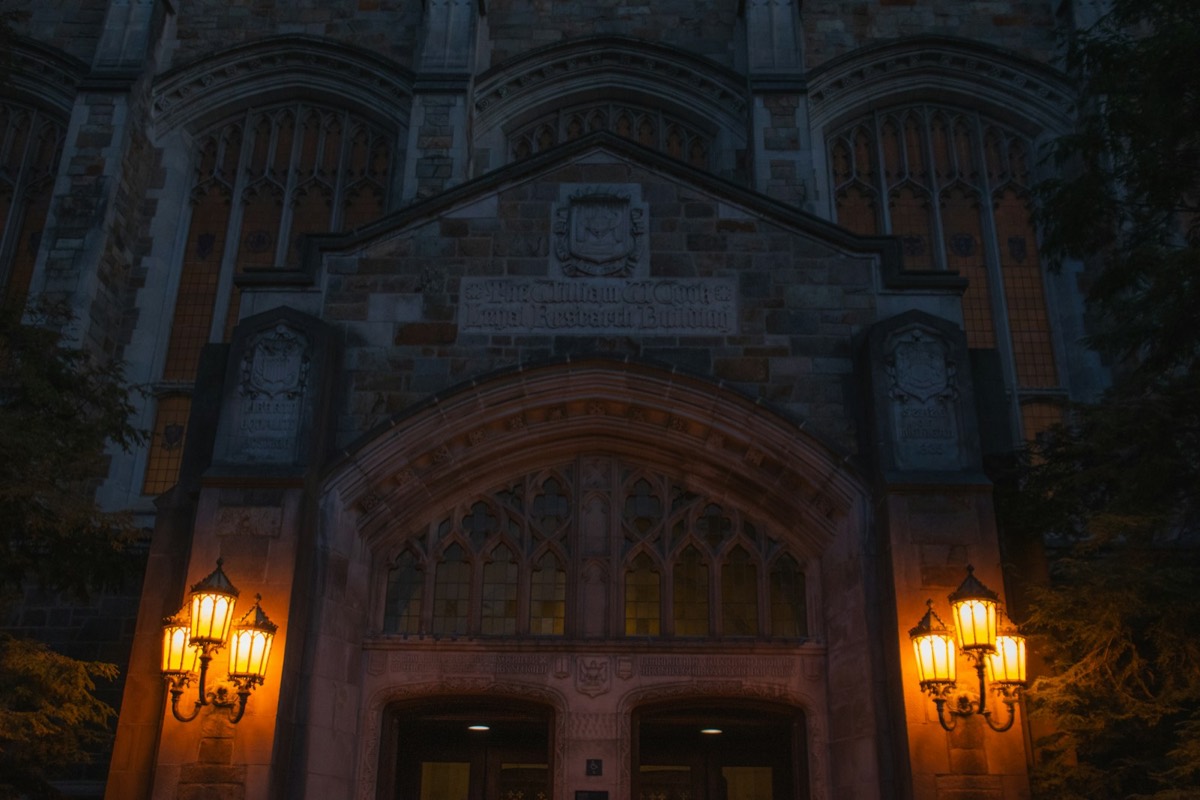 Gothic stone building entrance illuminated by warm glowing lanterns at night