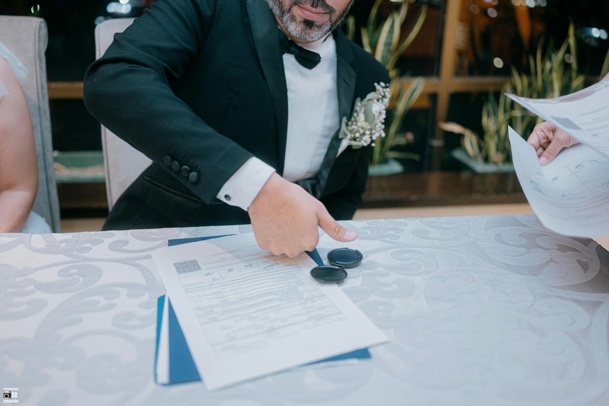 Man in tuxedo signing a document with keys