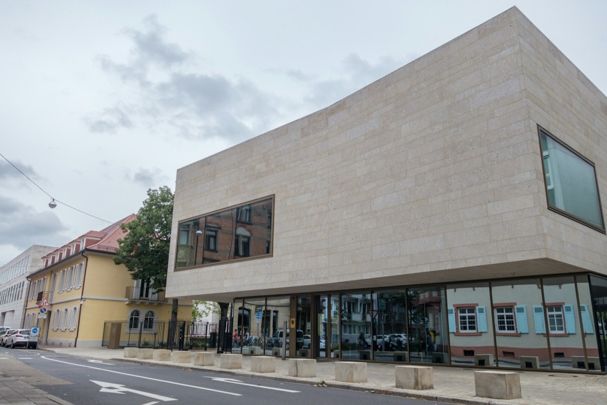 Modern concrete building with large windows beside an old building