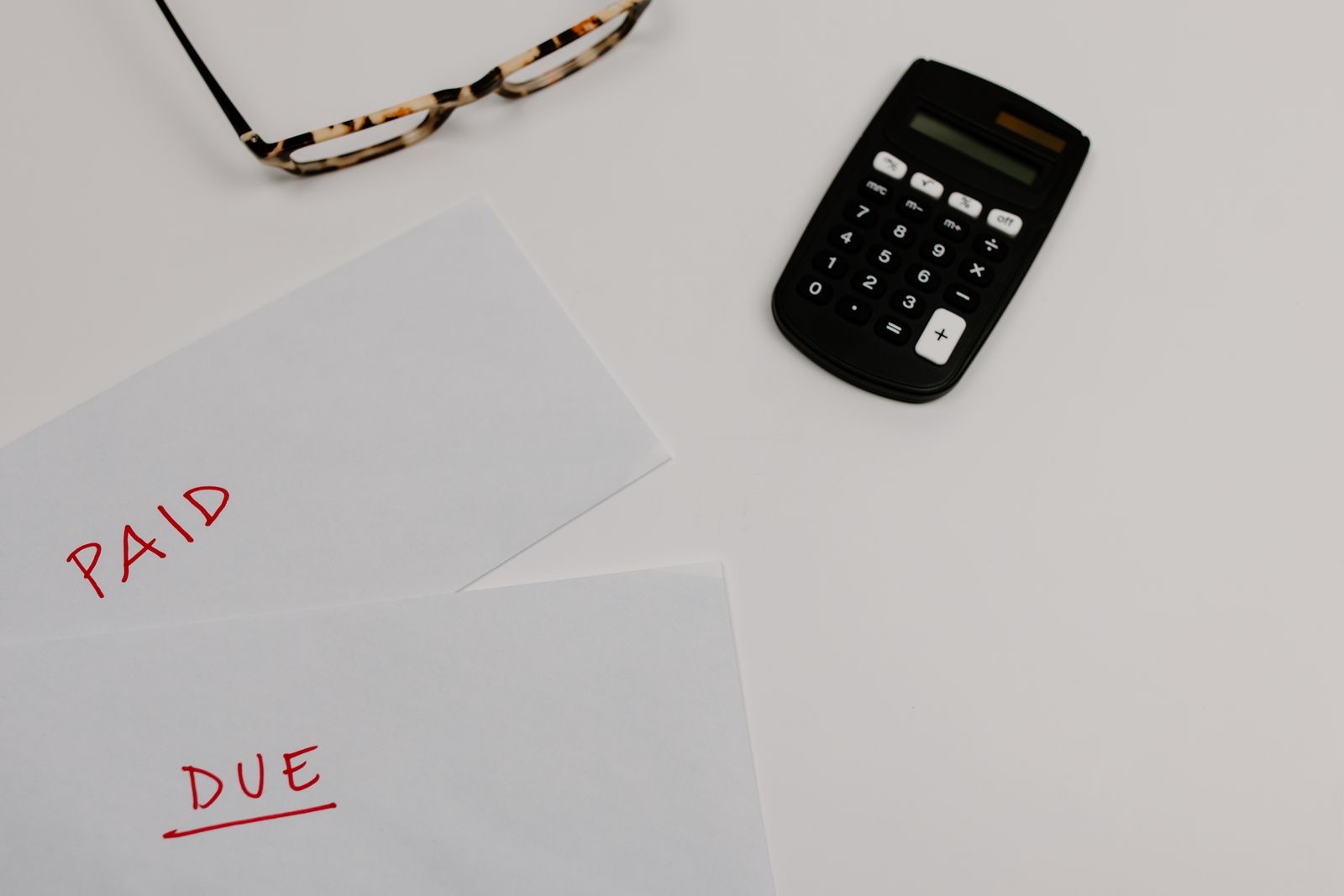 Papers marked paid and due beside a calculator