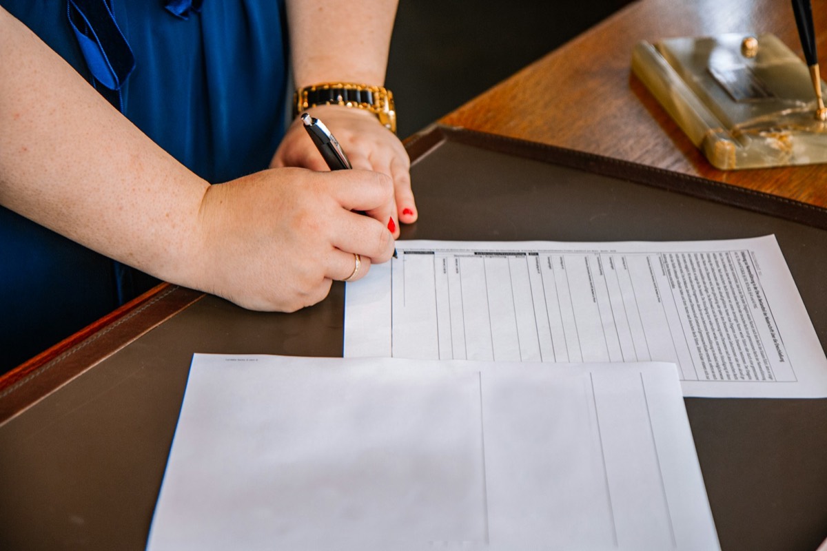 Person holding pen and writing on paper