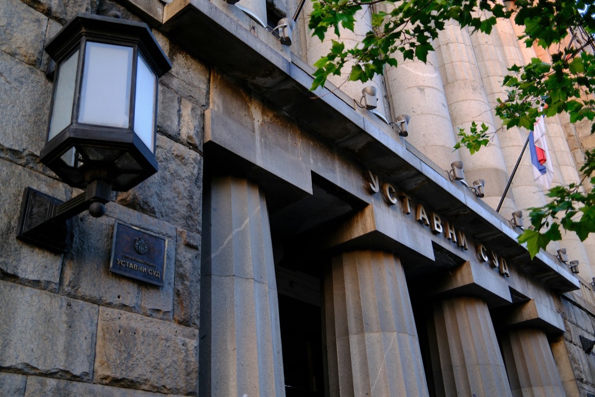 Stone building entrance with columns, a lantern, and carved text