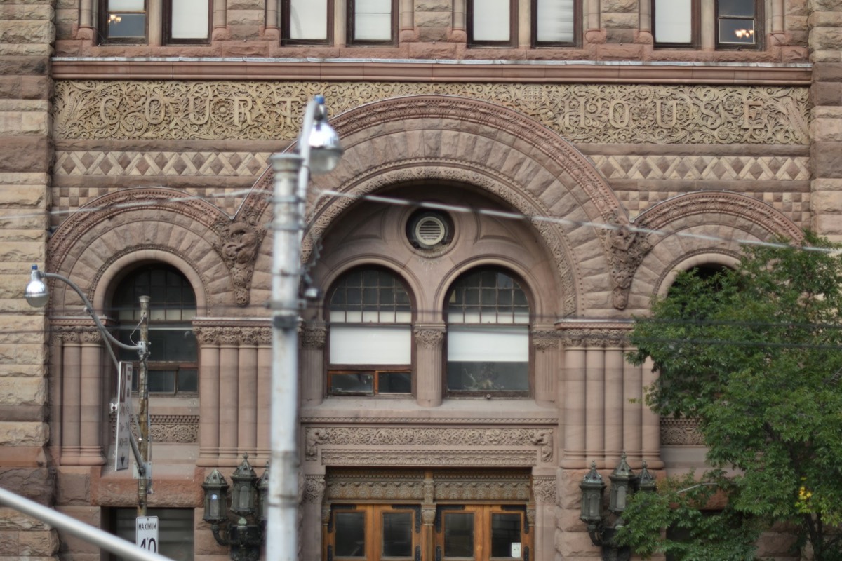 The stone facade of an old courthouse with arched windows and ornate carvings