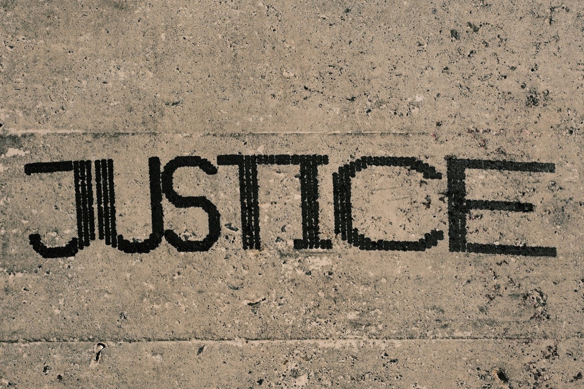 The word justice written in black ink on a concrete surface