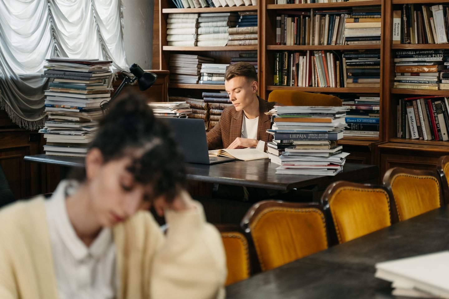 Young man reading in a library surrounded by books